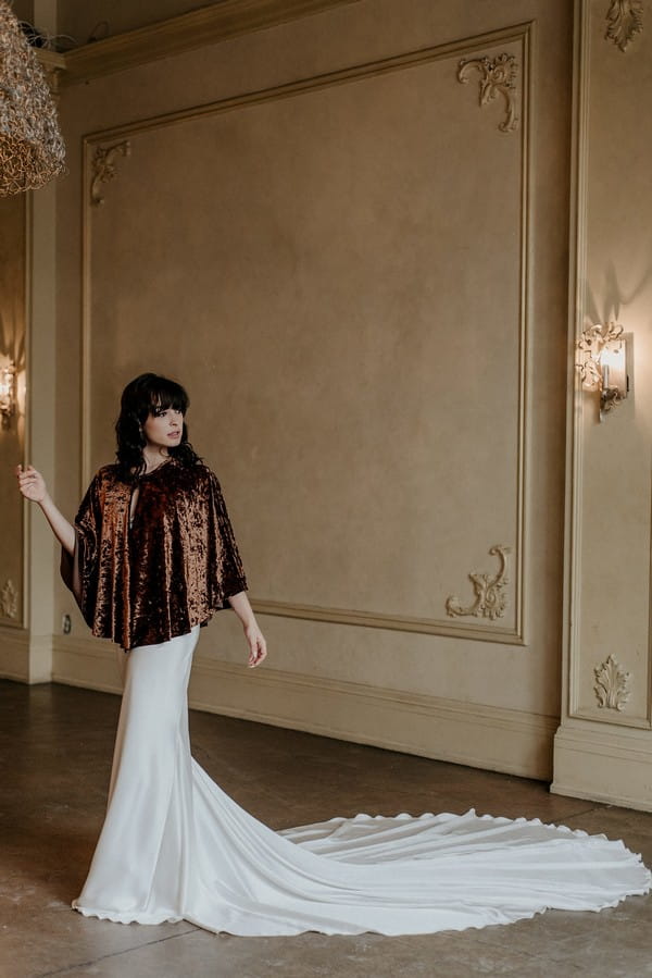 Bride wearing wedding dress with long train and velvet shrug