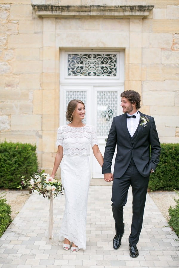 Bride and groom holding hands in front of Chateau de Redon