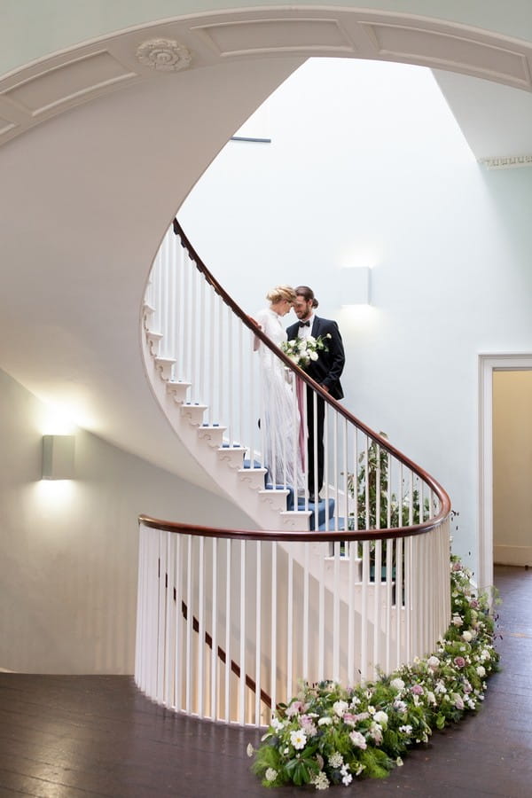 Bride and groom standing on spiral staircase at Clissold House