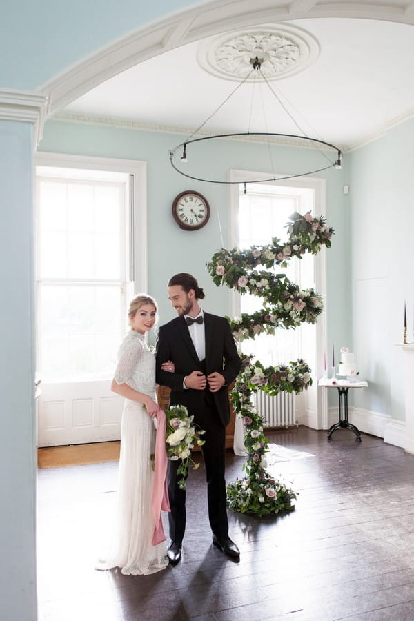 Bride and groom standing by spiral floral arrangement in Clissold House
