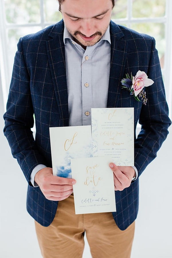 Groom holding wedding stationery