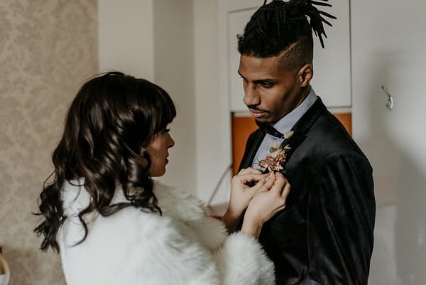 Bride helping groom with buttonhole