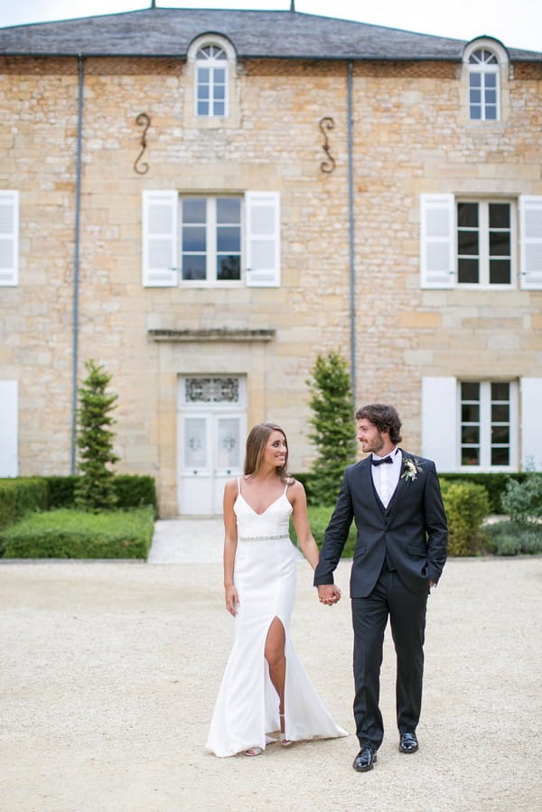 Bride and groom walking in front of Chateau de Redon