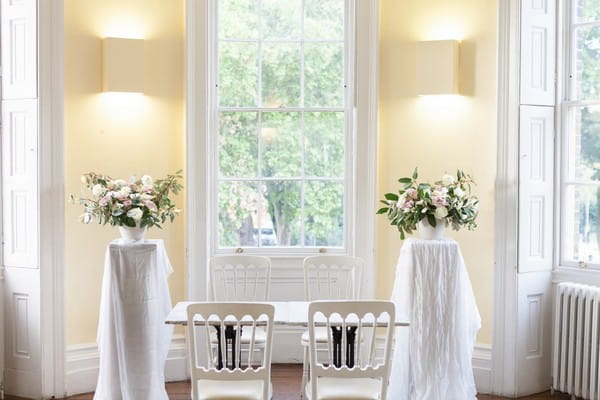 Chairs and floral arrangements at front of wedding ceremony room at Clissold House