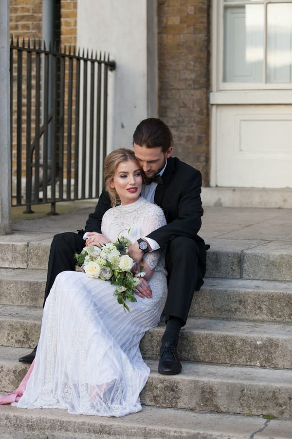 Bride and groom sitting on steps outside Clissold House