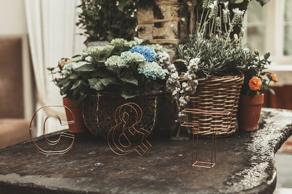 Table with baskets of wedding flowers and copper wire letters