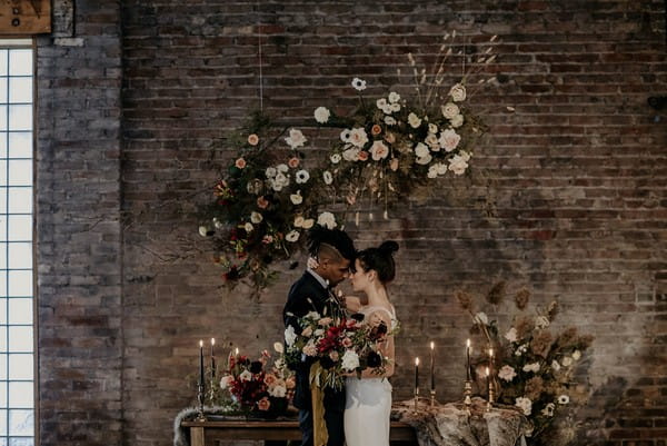 Bride and groom standing in front of table with autumn wedding styling and floral displays