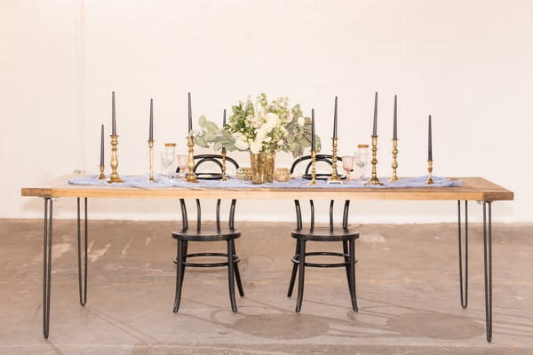 Wedding table in East Crossing with black chairs, gold candlesticks and floral centrepiece