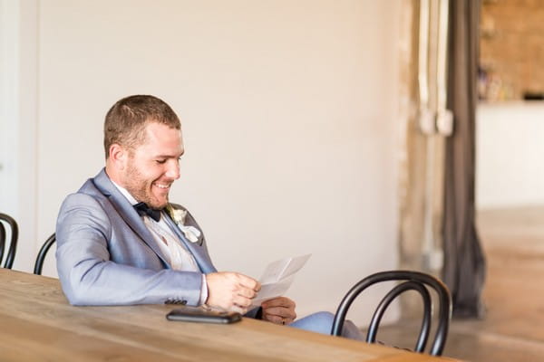 Groom smiling as he reads note from bride