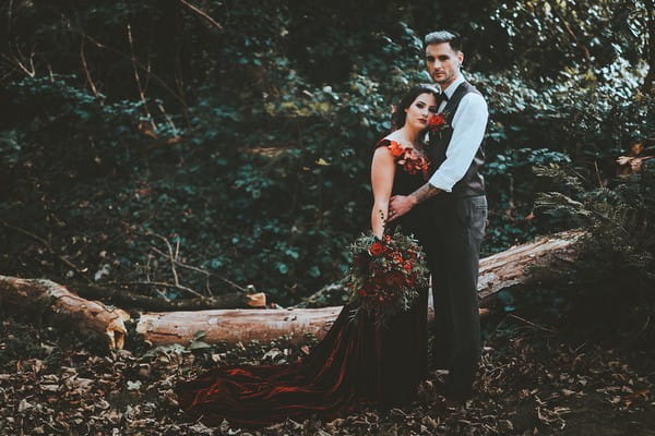Bride resting head against groom's chest in woods