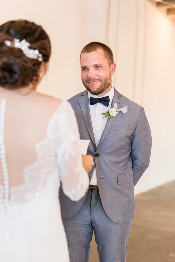 Groom smiling as bride reads wedding vows