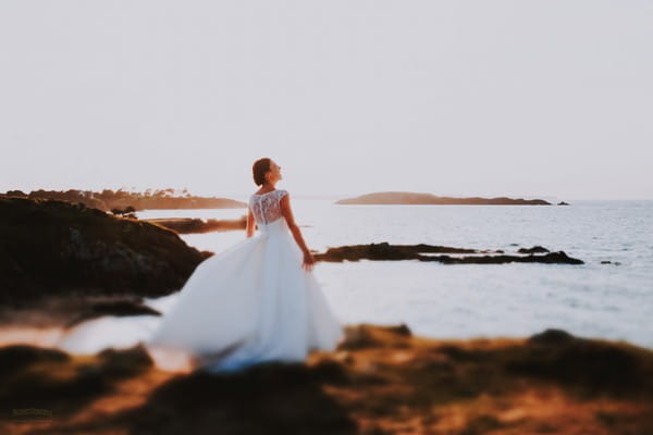 Bride standing by sea looking up at the sky - Picture by Patrice Dorizon