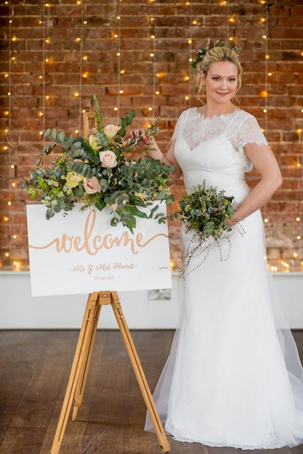 Bride standing next to wedding welcome sign