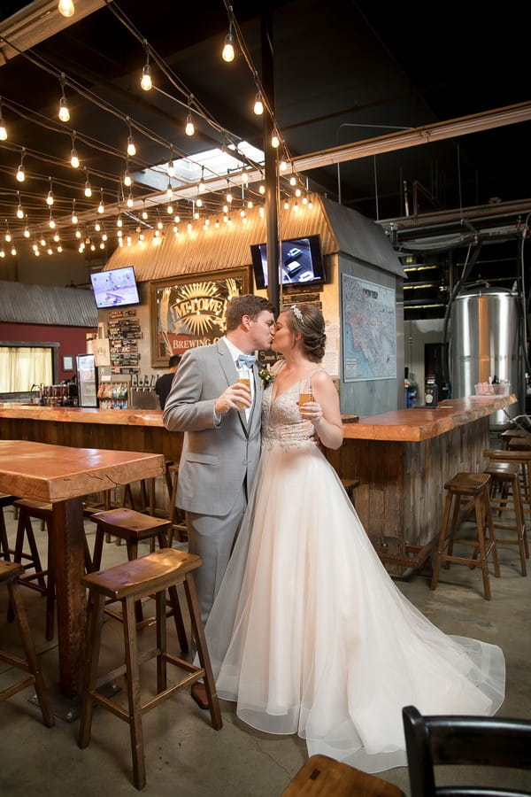 Bride and groom kissing by bar in Mt. Lowe Brewery