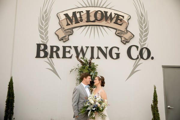 Bride and groom kissing in front of Mt. Lowe Brewing Co. sign