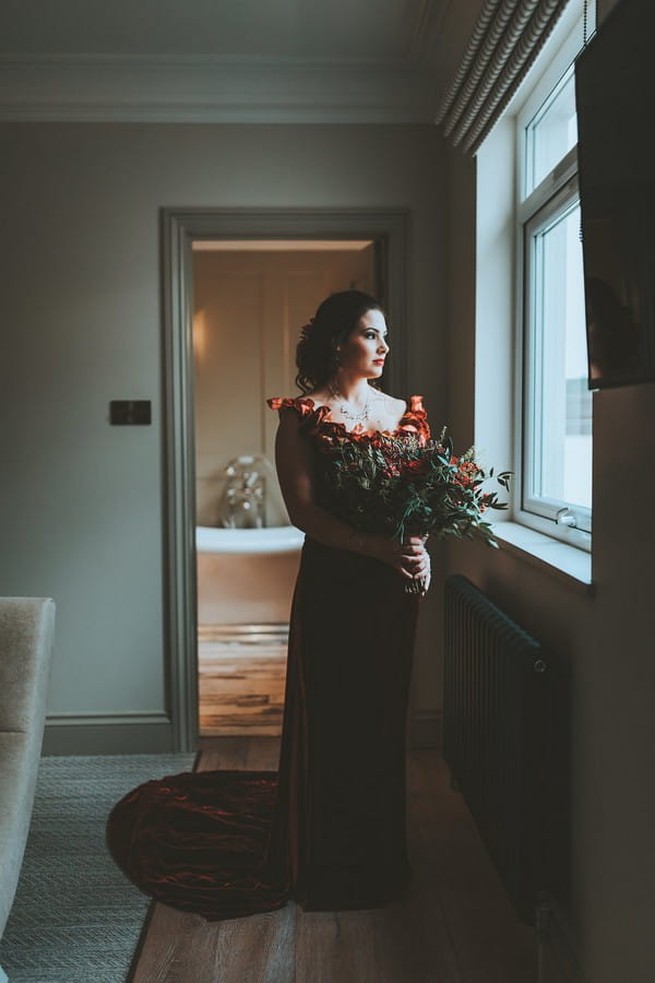 Bride holding bouquet looking out of window