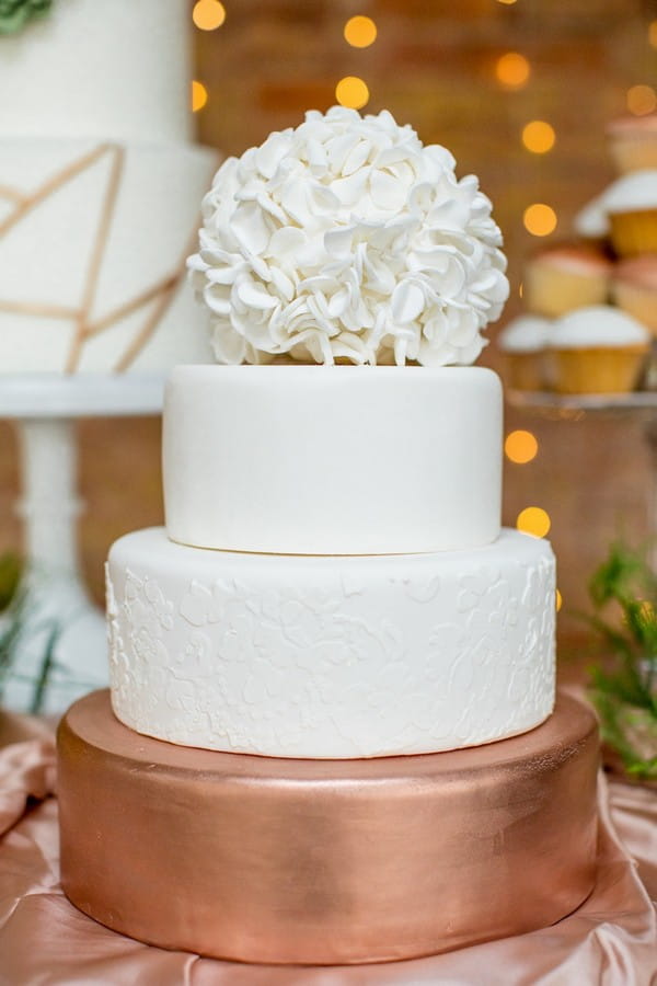 Copper and white wedding cake topped with sugar hydrangea head