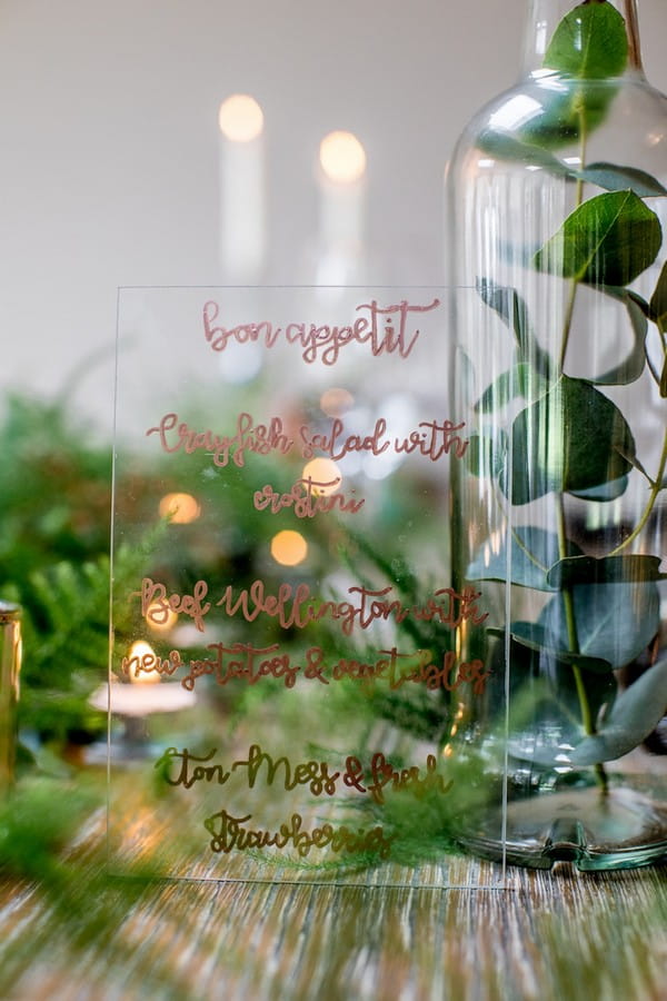 Wedding menu written in gold lettering on glass