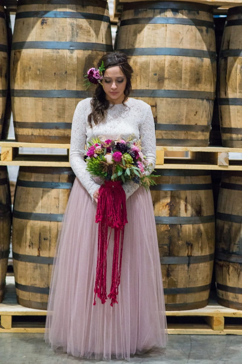 Bride holding bouquet in front of barrels at Breckenridge Distillery