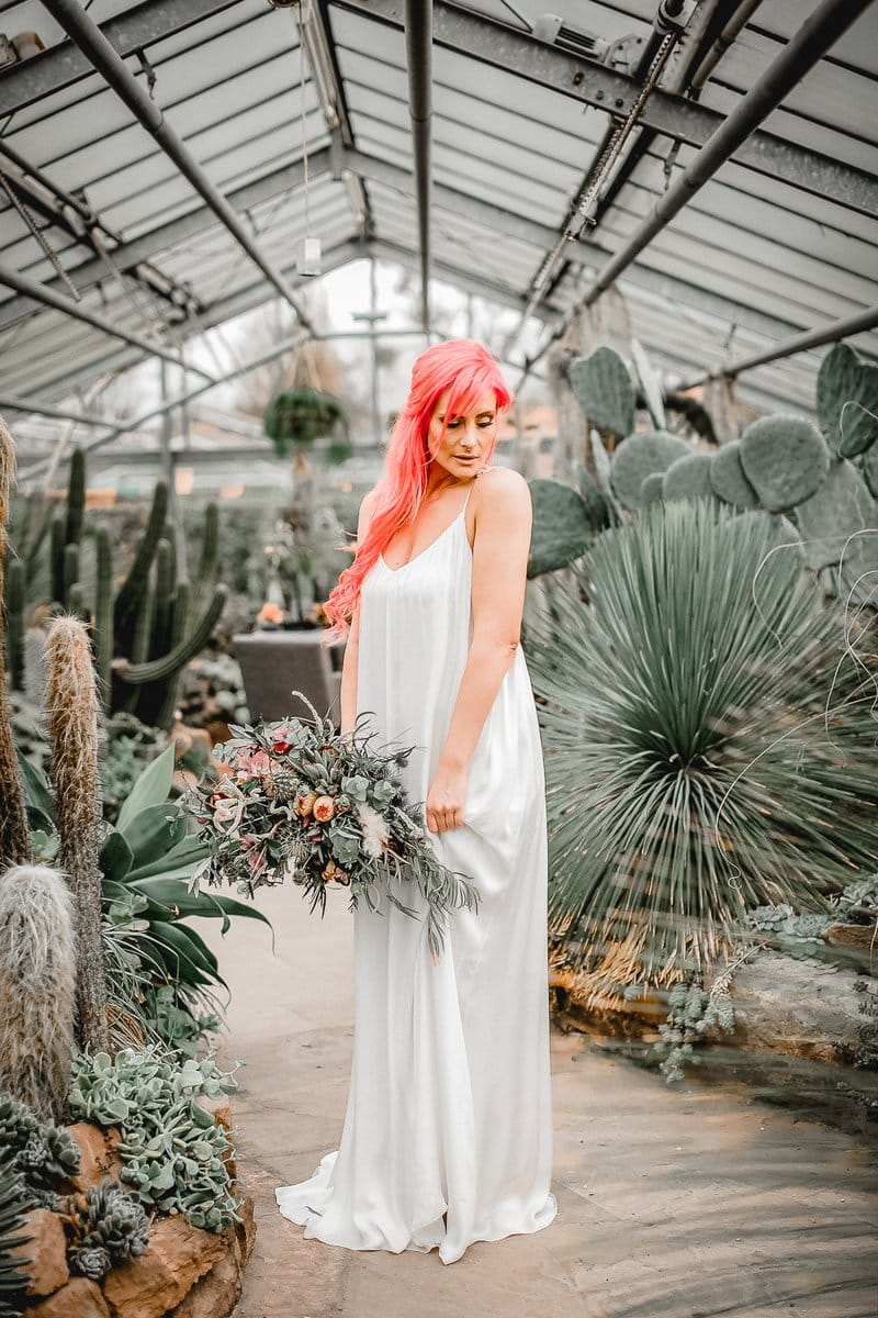 Bride holding bouquet in greenhouse full of cactuses