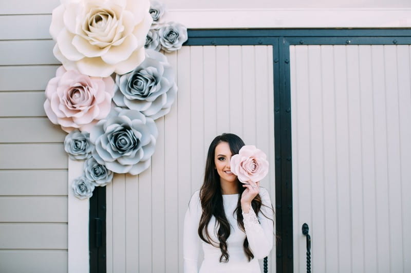 Bride standing by paper flower backdrop