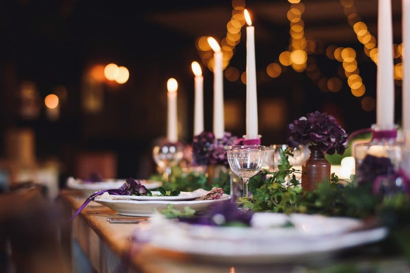 Candles and plates on rustic table to create hygge wedding styling