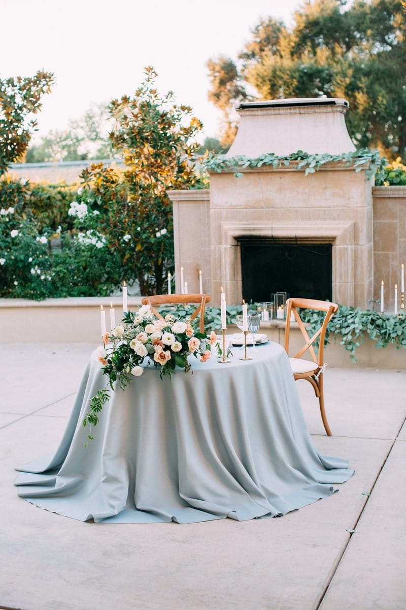 Small wedding table with dusty blue tablecloth and pastel wedding flowers