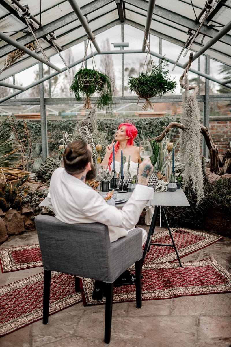 Bride and groom sitting at wedding table in greenhouse