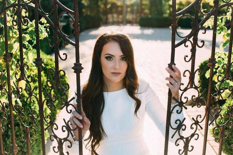 Bride standing holding doors to gate at Scribner Bend Vineyards