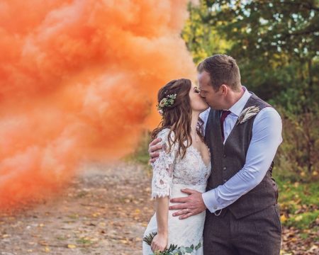 Bride and groom kising next to orange smoke - Picture by Rebecca Gurden Photography