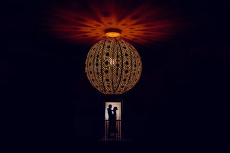 Silhouette of bride and groom under beautiful light fitting - Picture by Fiona Walsh Photography
