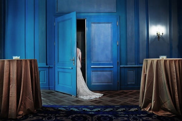 Bride leaving room through blue door - Picture by Franck Boutonnet Photography