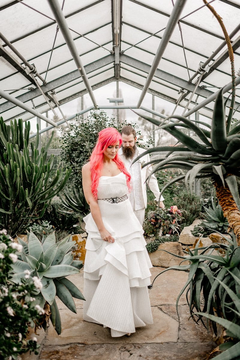 Bride leading groom by the hand through greenhouse full of cactuses