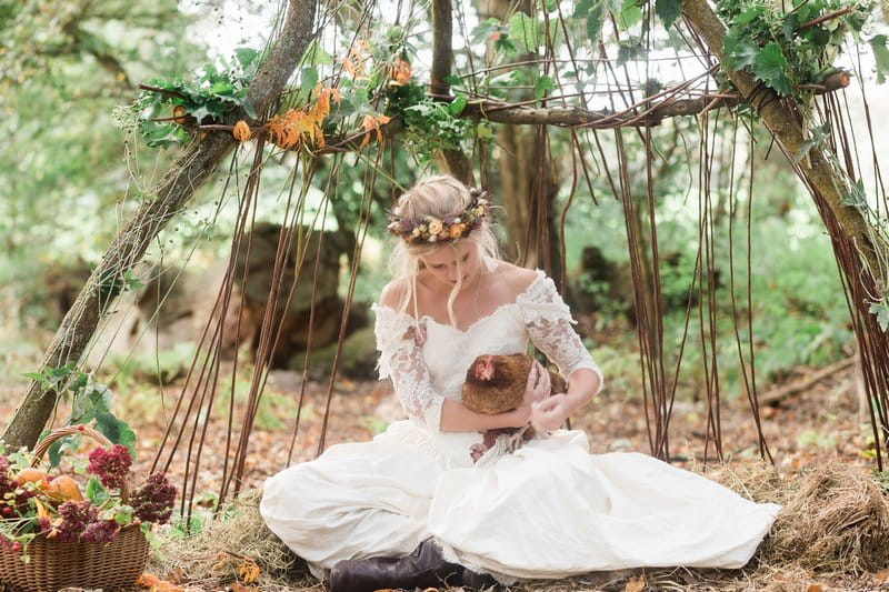 Bride sitting in woodland holding chicken