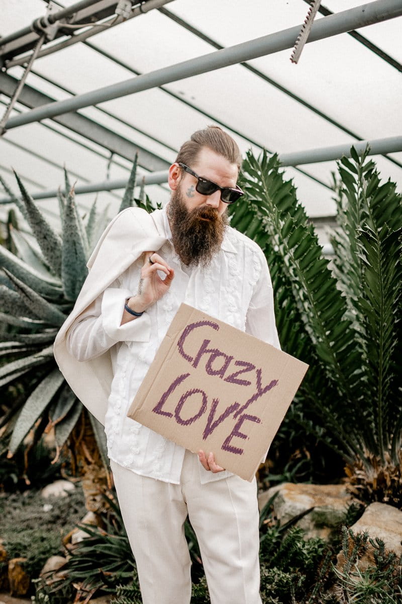 Groom with sunglasses holding sign saying Crazy Love