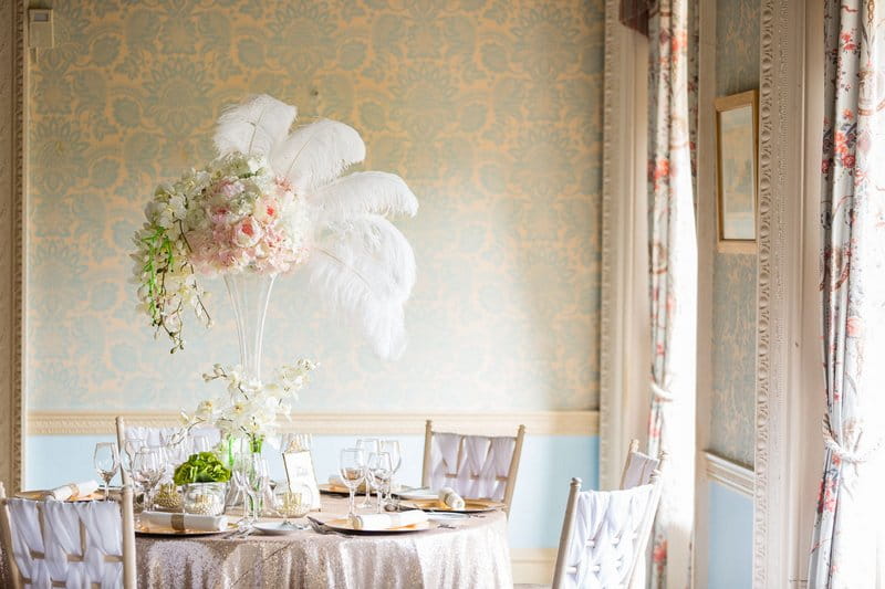 Wedding table with vintage styling including floral and feather centrepiece