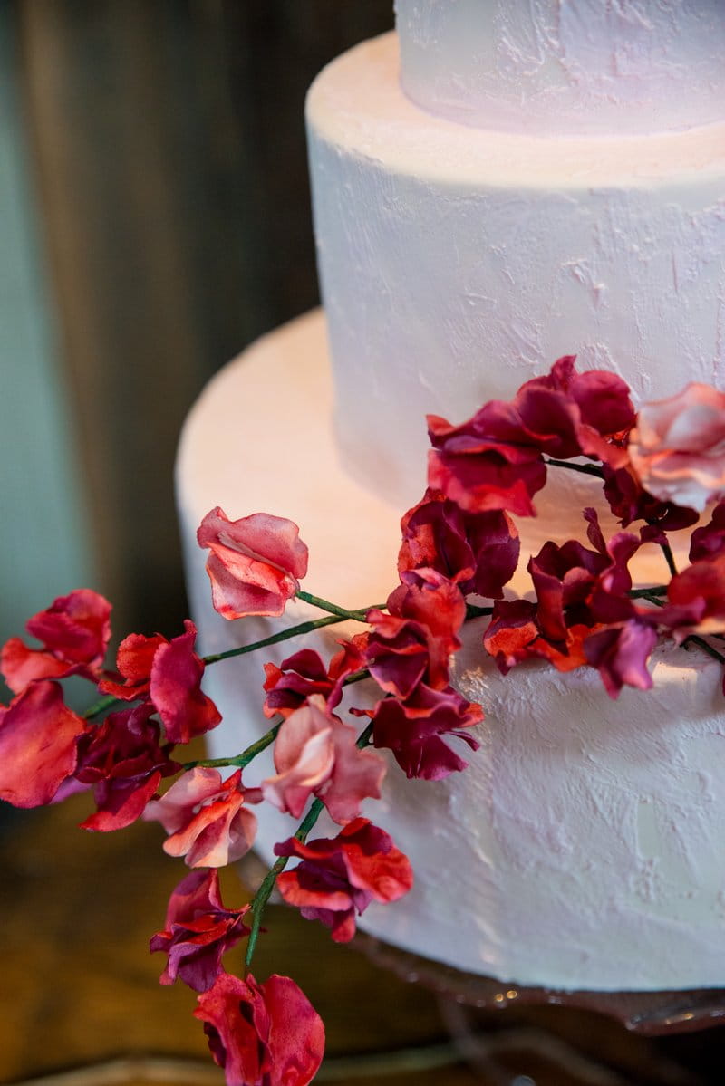 Red flowers on plain white wedding cake