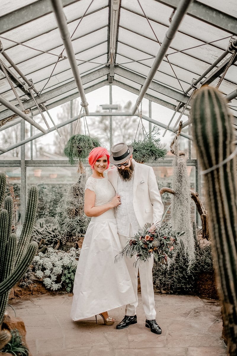 Bride with pink hair and groom in white suit and hat