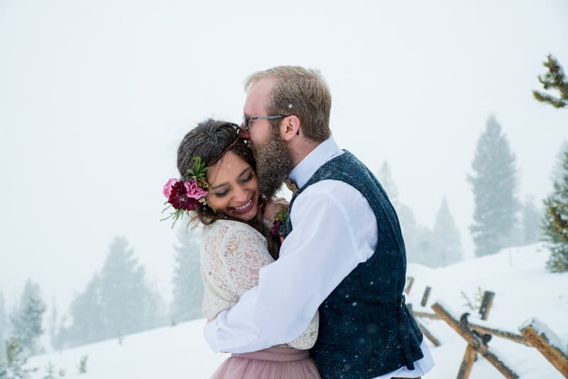 Groom kissing bride on side of head in the snow