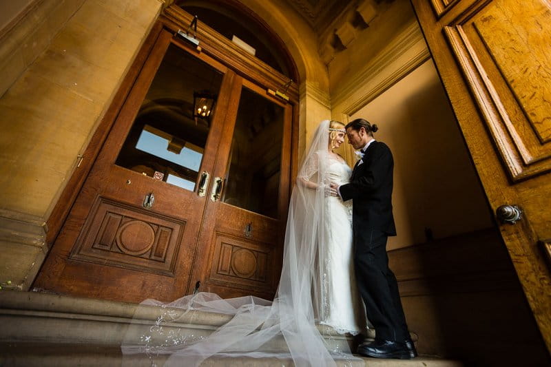 Bride and groom standing by entrance to Heythrop Park