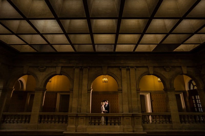 Bride and groom standing on gallery of Heythrop Park