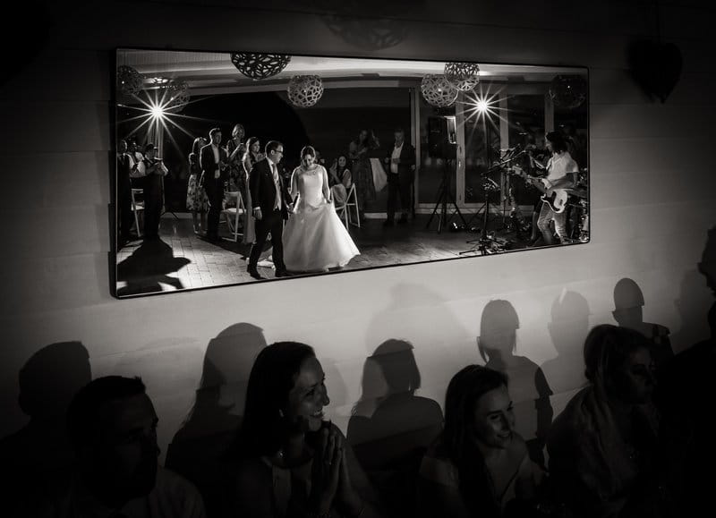 Reflectiojn in mirror of bride and groom walking onto dance floor