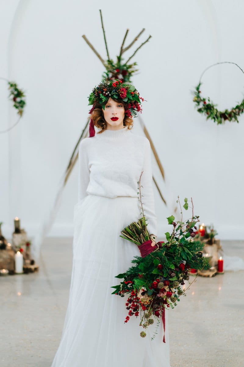 Bride wearing foliage and red berries crown carrying winter wedding bouquet