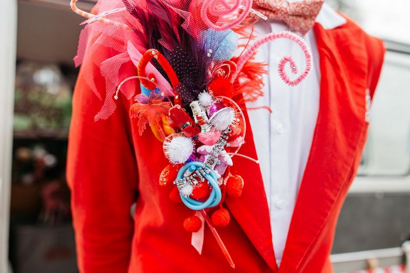 Red lapel piece made from pom poms, pipe cleaners and toys