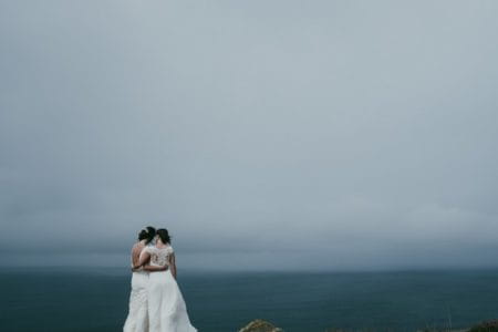 Two bride standing looking looking out to sea - Picture by Ross Talling Photography