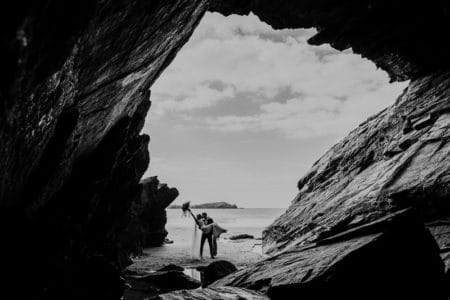 Picture taken from cave of bride and groom kissing on beach - Picture by Alexa Poppe Wedding Photography