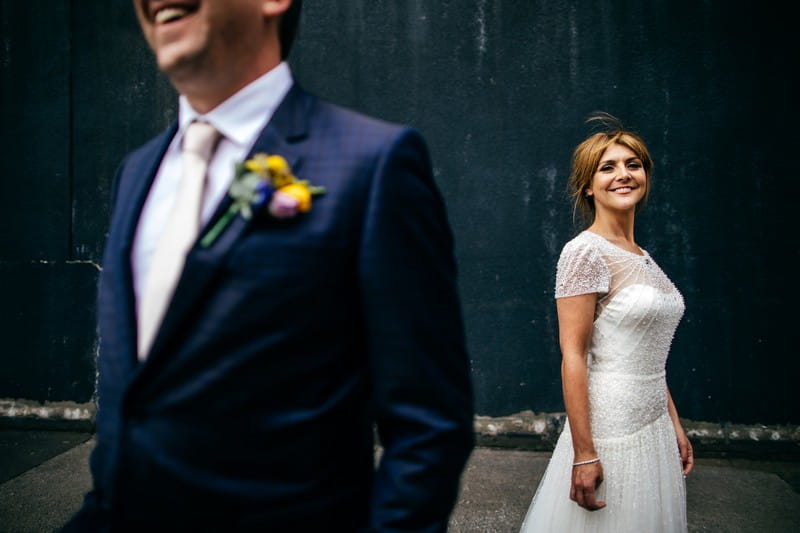 Bride in background smiling with groom in foreground - Picture by Jordanna Marston Photography