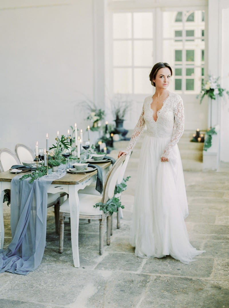 Elegant bride standing next to wedding table with grey styling