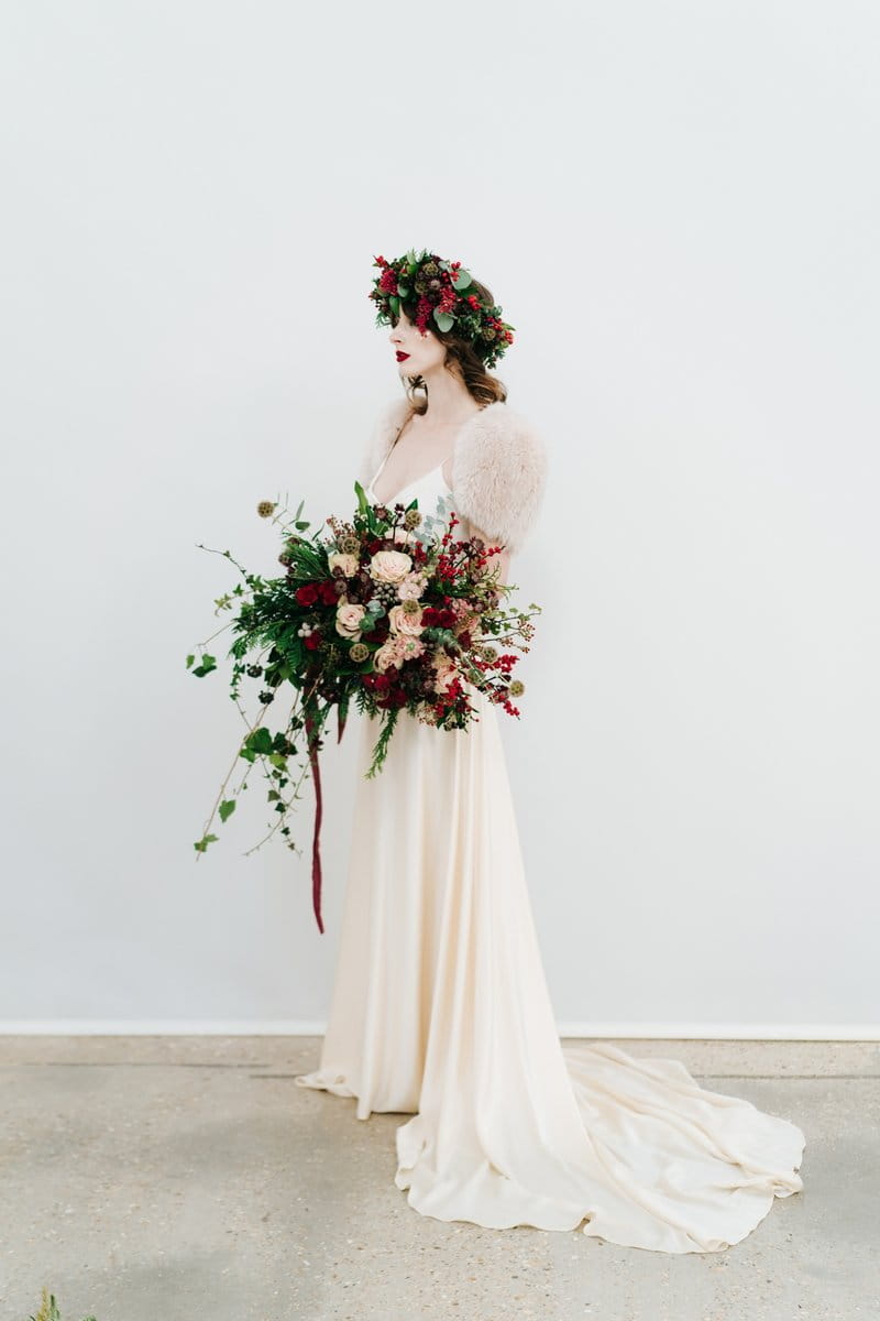 Bride with red berry and foliage crown holding large winter wedding bouquet