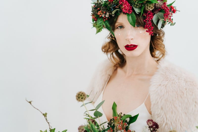 Winter bride wearing foliage and red berry crown and holding bouquet